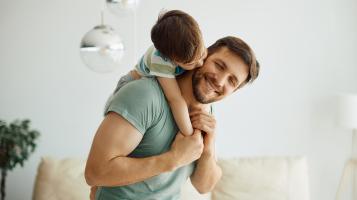 ojciec z dzieckiem na ramionach